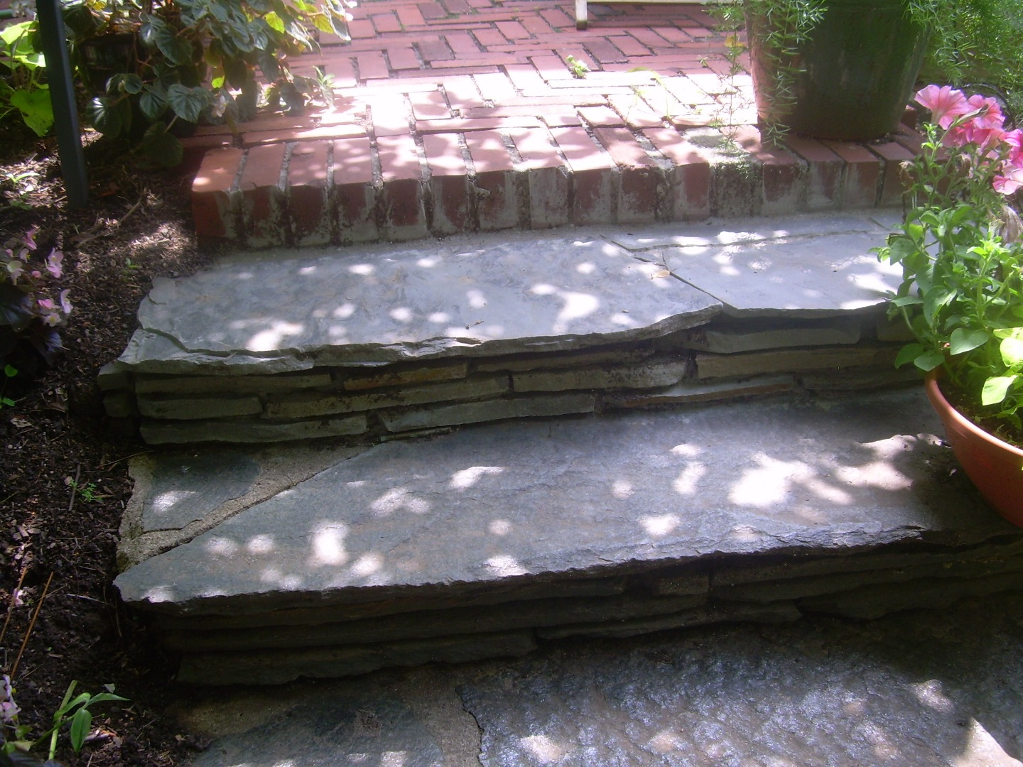 Layered natural-stone garden steps beneath dappled shade